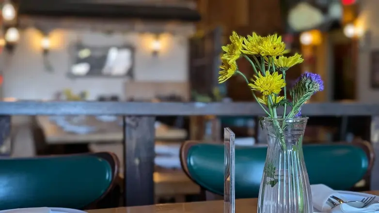 Yellow flowers in a glass vase on a dining table