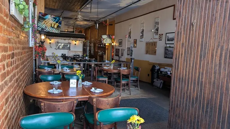 Round tables and teal chairs beside the brick wall