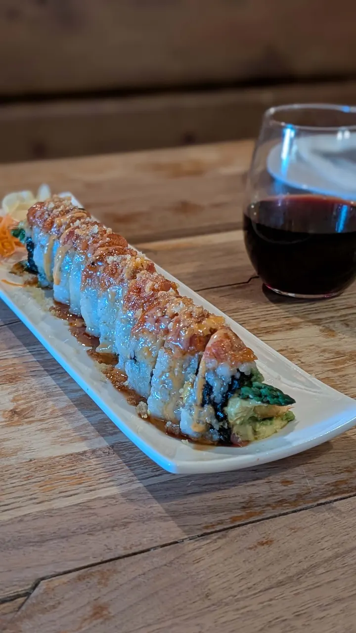 A sushi roll beside a glass of red wine